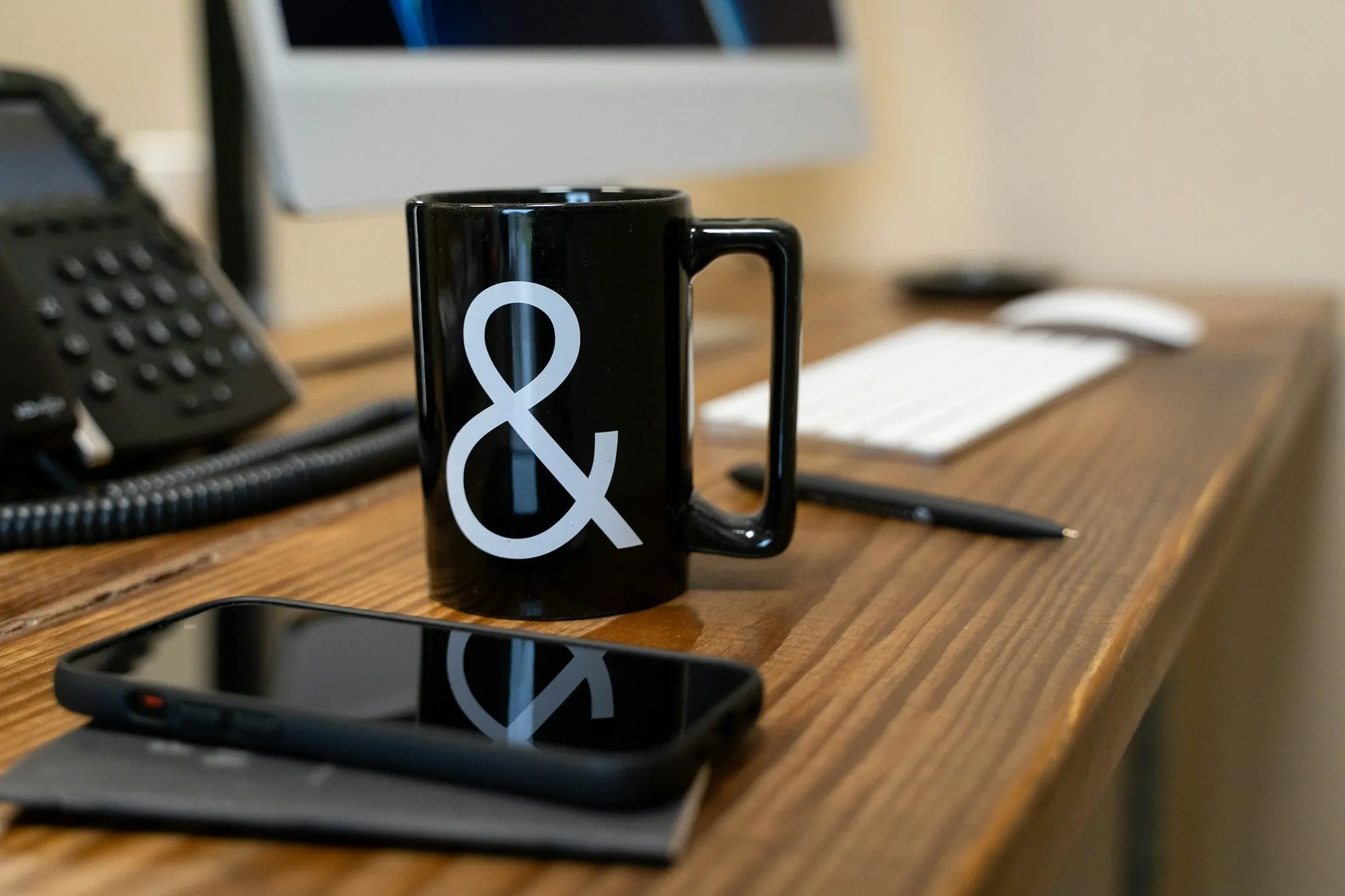 Office desk with a coffee mug, phone and keyboard