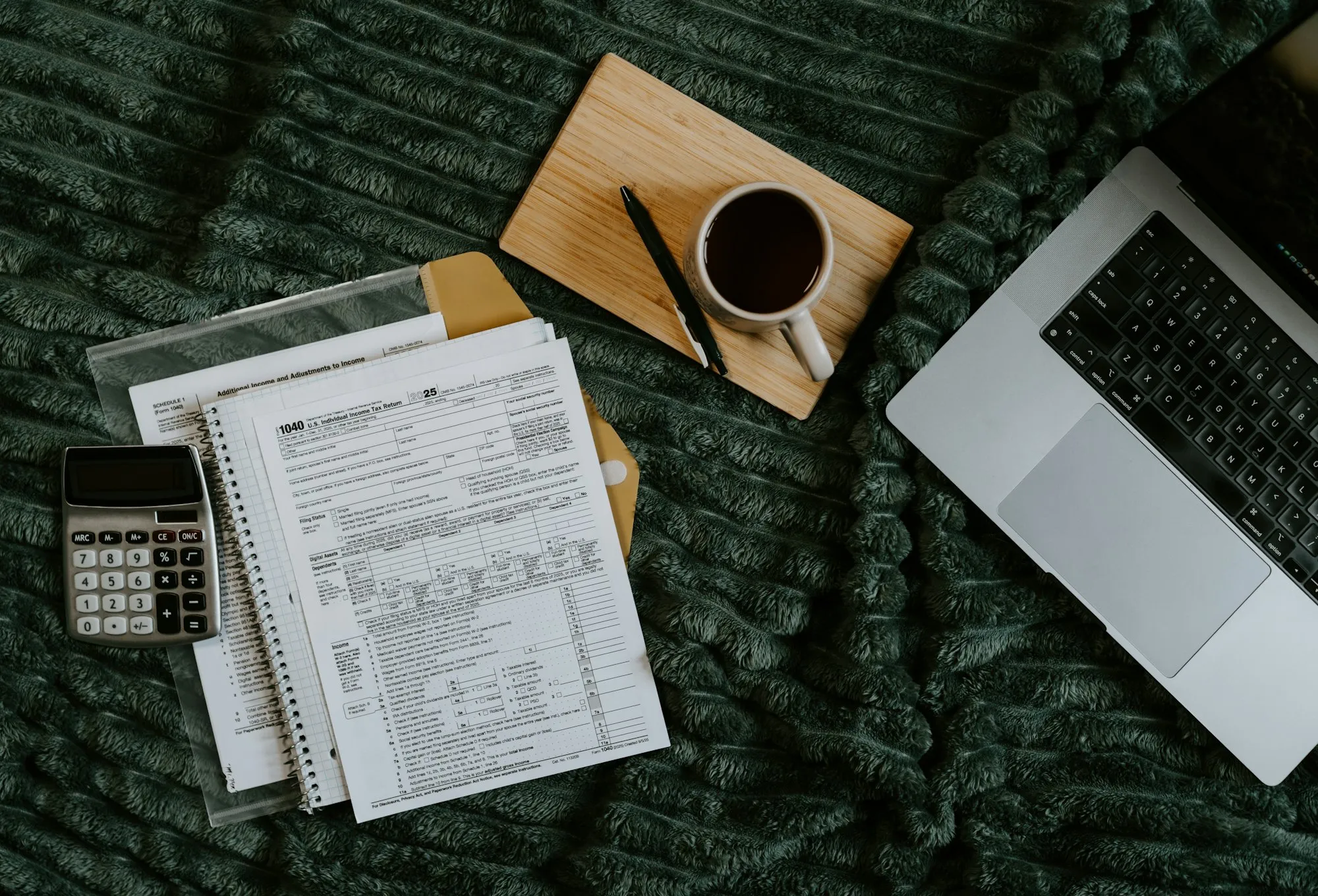 Tax documents, calculator and laptop on a desk